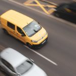 a yellow car and a white car on a road