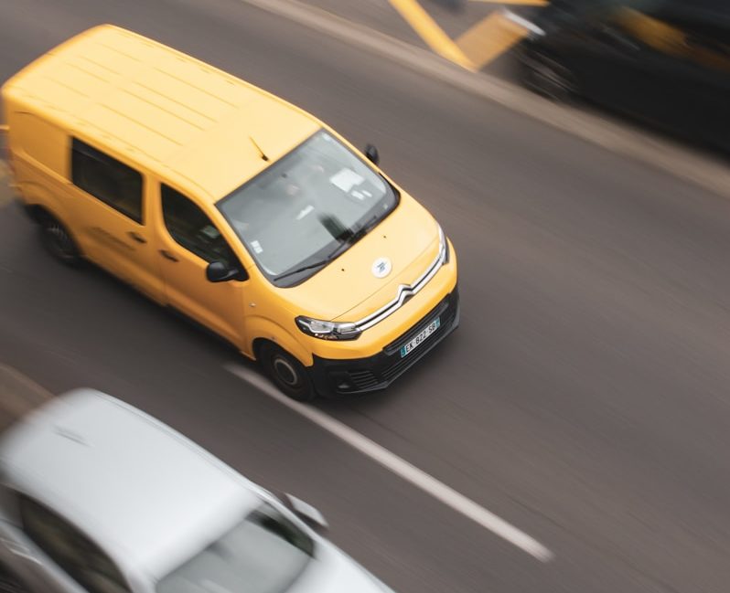 a yellow car and a white car on a road