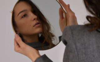 woman in gray long sleeve shirt holding her head