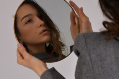 woman in gray long sleeve shirt holding her head