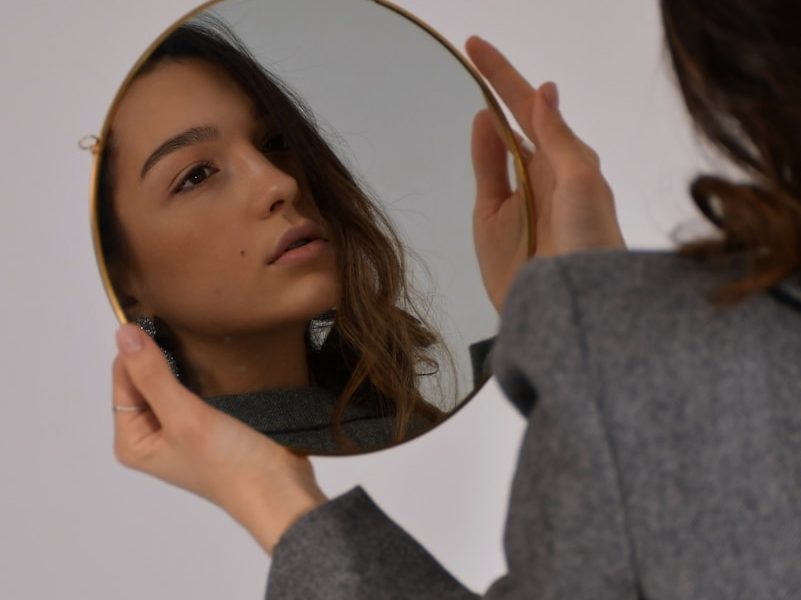 woman in gray long sleeve shirt holding her head