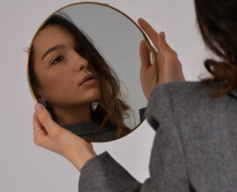 woman in gray long sleeve shirt holding her head